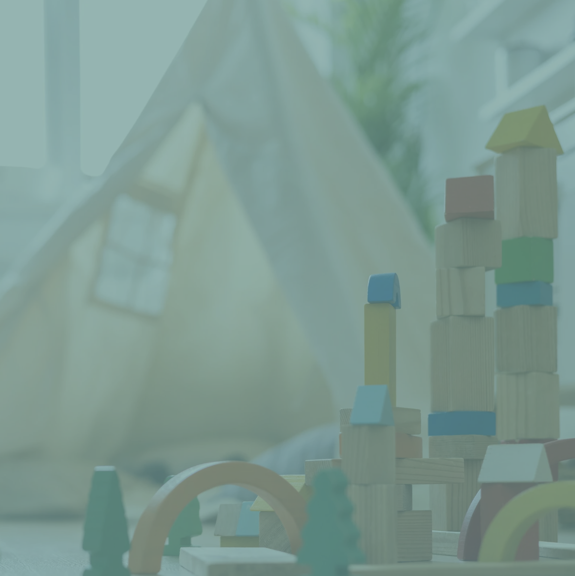 Wooden building blocks up close with a teepee tent in the background, the entire image is tinted in a pale green