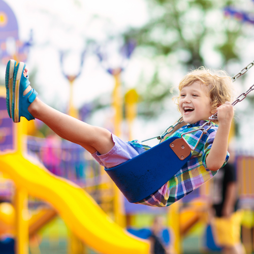 Kid laughing while swinging on a playground<br />
