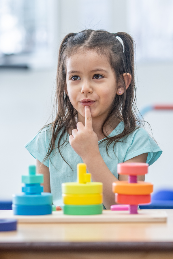 Child putting finger up towards lips in a speech therapy session